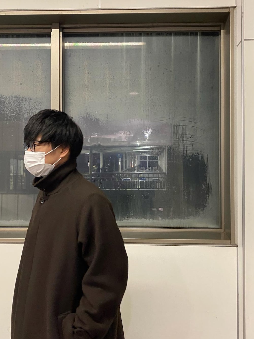 ブラウン系のステンカラーコート、ブルー系のデニムパンツ、ブラック系のブーツを着用したメンズの冬コーディネートの3枚目の写真