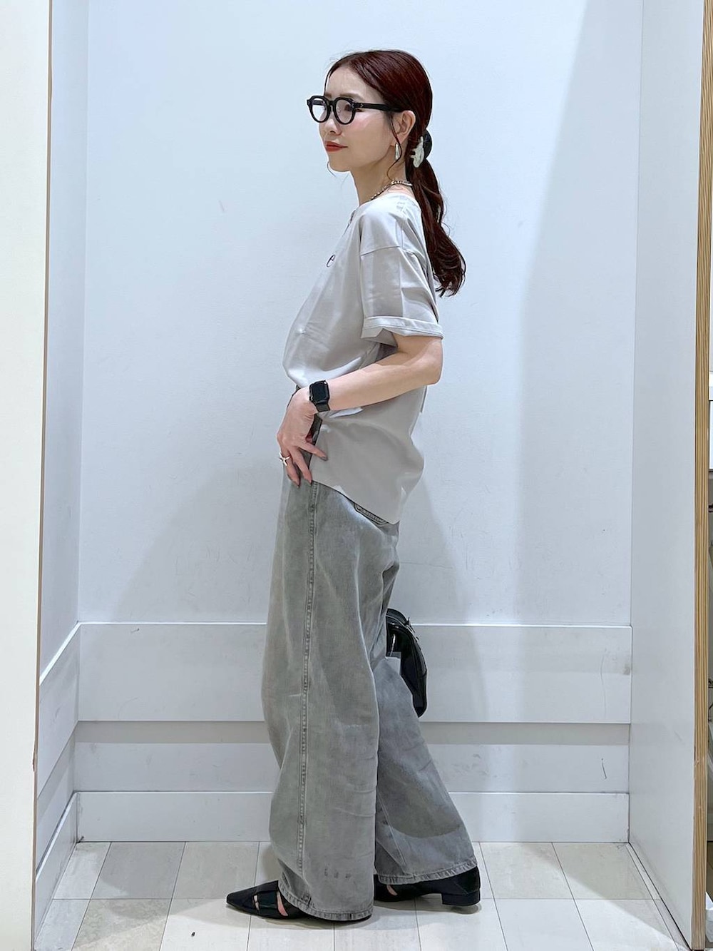 グレー系のデニムパンツ、ブラック系のボストンバッグ、ベージュ系のTシャツ/カットソーを着用したレディースの春コーディネートの2枚目の写真