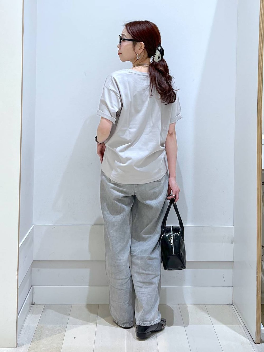 グレー系のデニムパンツ、ブラック系のボストンバッグ、ベージュ系のTシャツ/カットソーを着用したレディースの春コーディネートの3枚目の写真