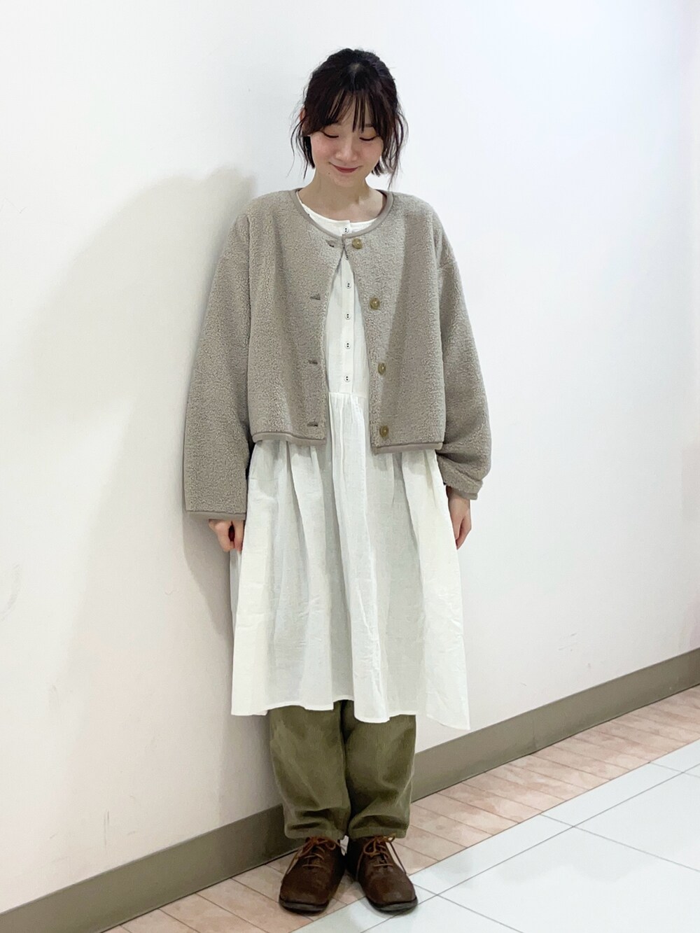 ホワイト系のチュニック、ベージュ系のブルゾン、グリーン系のその他パンツを着用したレディースの秋コーディネートの2枚目の写真