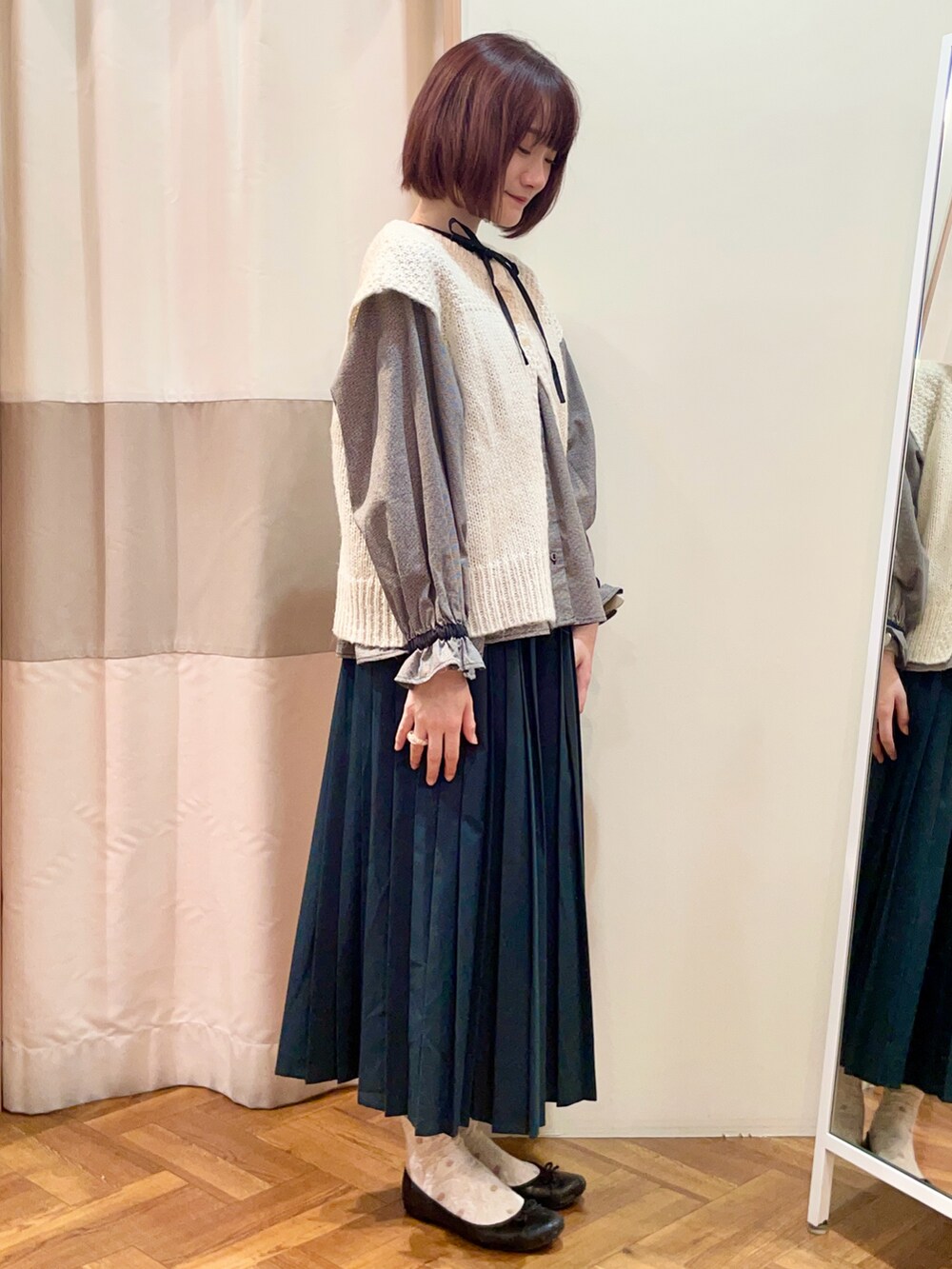 グレー系のスカート、ブラック系のシャツ/ブラウス、ホワイト系のベストを着用したレディースの冬コーディネートの2枚目の写真