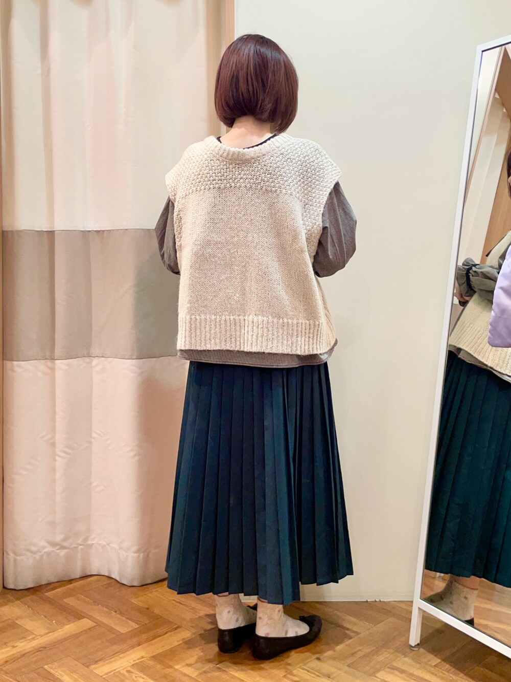 グレー系のスカート、ブラック系のシャツ/ブラウス、ホワイト系のベストを着用したレディースの冬コーディネートの3枚目の写真