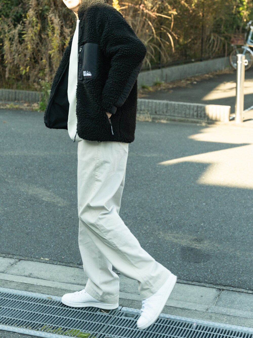 ブラック系のブルゾン、ホワイト系のトップス、ホワイト系のパンツを着用したメンズの冬コーディネートの4枚目の写真