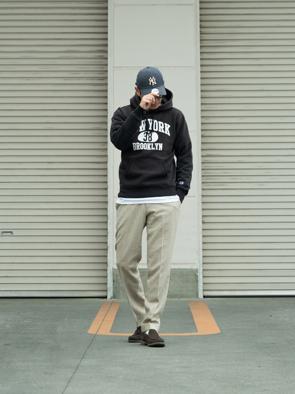 ブラック系のパーカー、ベージュ系のパンツ、ブラウン系のシューズを着用したメンズの冬コーディネートの2枚目の写真