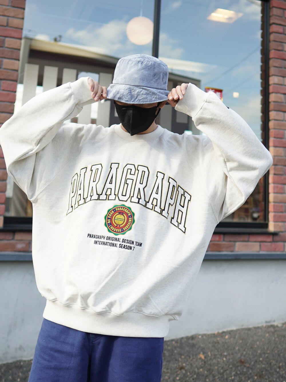 ブルー系のデニムパンツ、ホワイト系のスニーカー、ホワイト系のスウェットを着用したメンズの春コーディネートの2枚目の写真