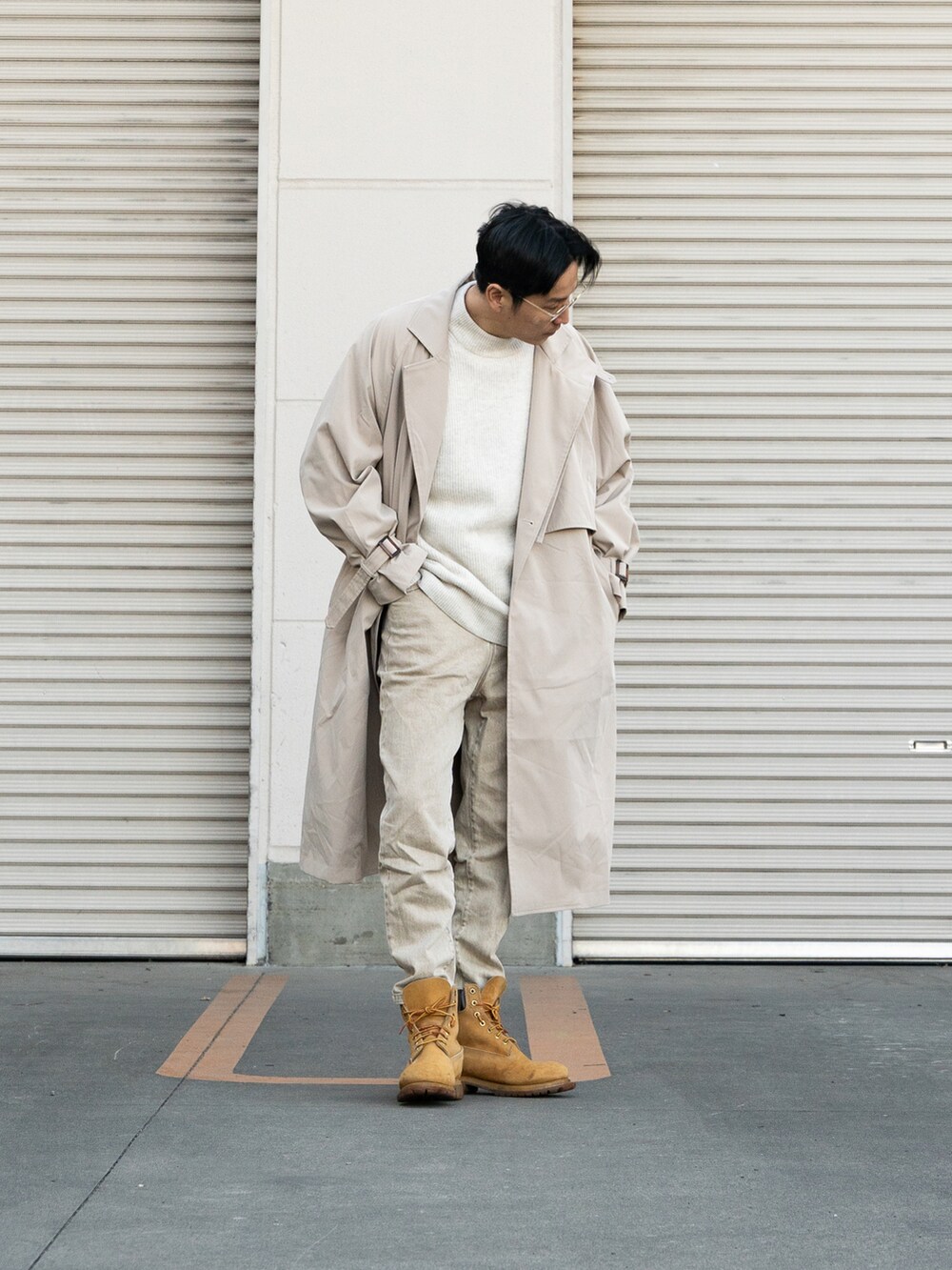 イエロー系のブーツ、ベージュ系のトレンチコート、ホワイト系のトップスを着用したメンズの冬コーディネートの3枚目の写真
