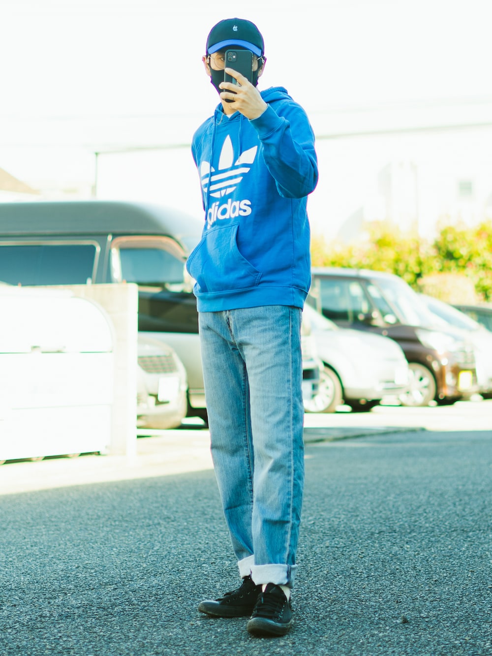 ブルー系のパーカー、ブルー系のデニムパンツ、ブラック系のスニーカーを着用したメンズの秋コーディネートの3枚目の写真