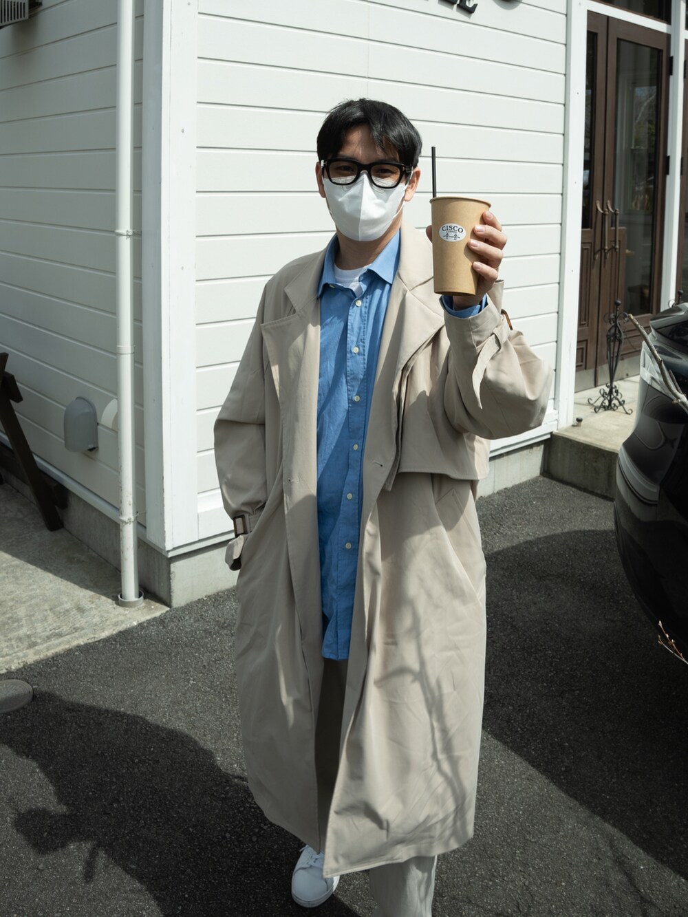 ブルー系のシャツ/ブラウス、ベージュ系のトレンチコート、ホワイト系のパンツを着用したメンズの春コーディネートの3枚目の写真