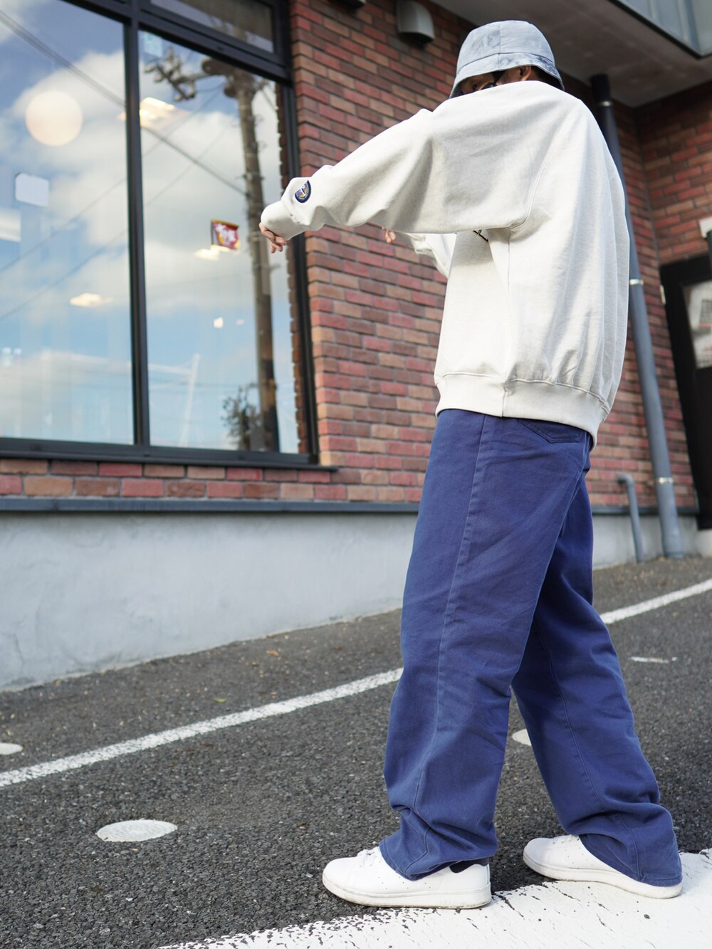 ブルー系のデニムパンツ、ホワイト系のスニーカー、ホワイト系のスウェットを着用したメンズの春コーディネートの3枚目の写真