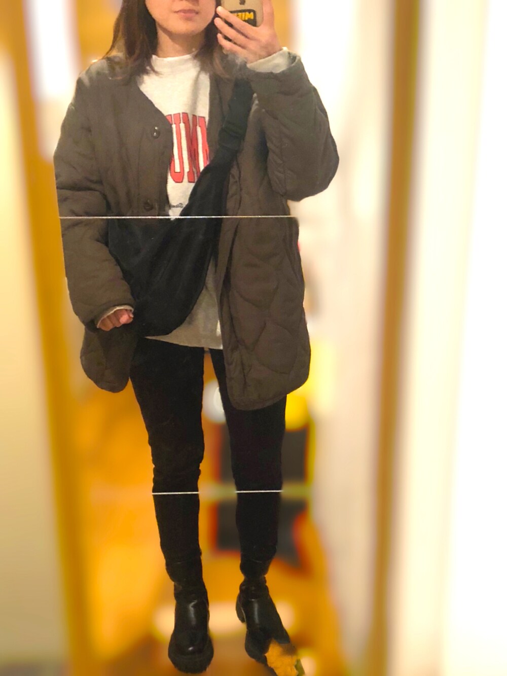 グリーン系のミリタリージャケット、ブラック系のパンツ、ブラック系のブーツを着用したレディースの秋コーディネートの2枚目の写真