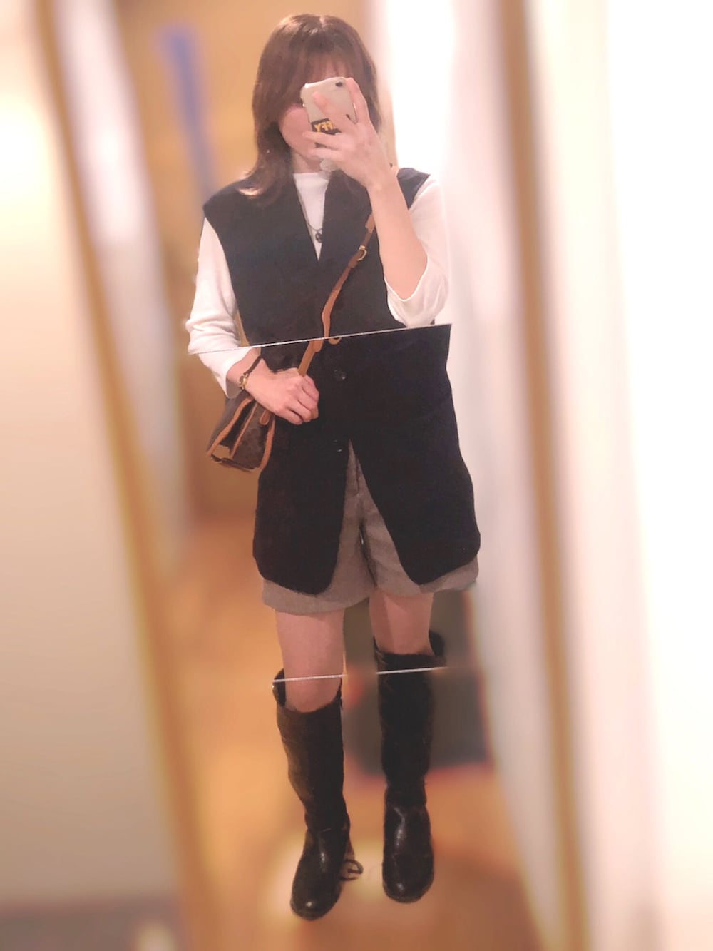 ブラウン系のショルダーバッグ、ブルー系のベスト、ブラック系のブーツを着用したレディースの秋コーディネートの2枚目の写真