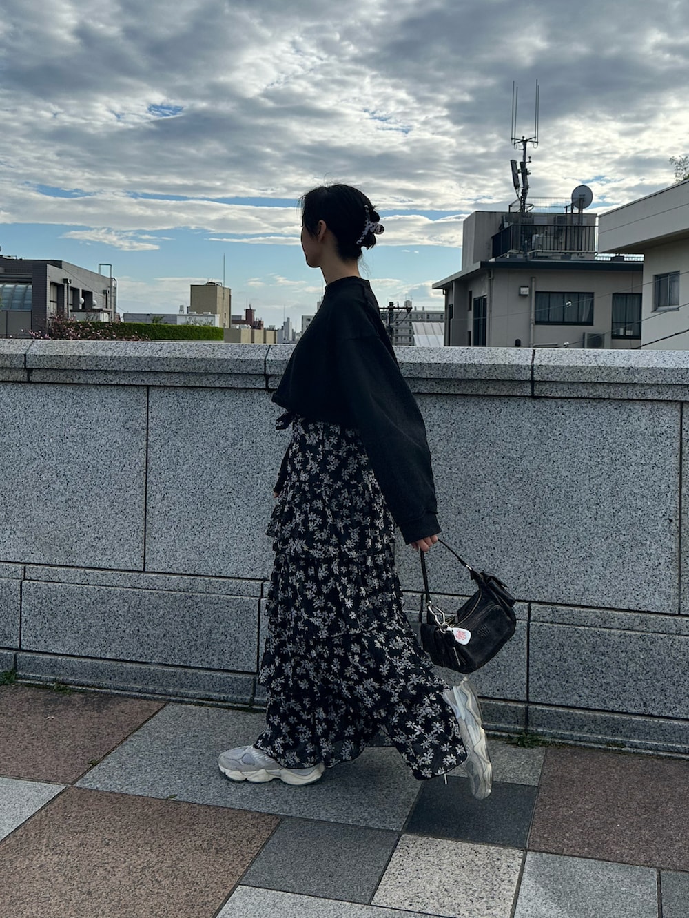 ブラック系のハンドバッグ、ブラック系のスウェット、ブラック系のスカートを着用したレディースの春コーディネートの2枚目の写真