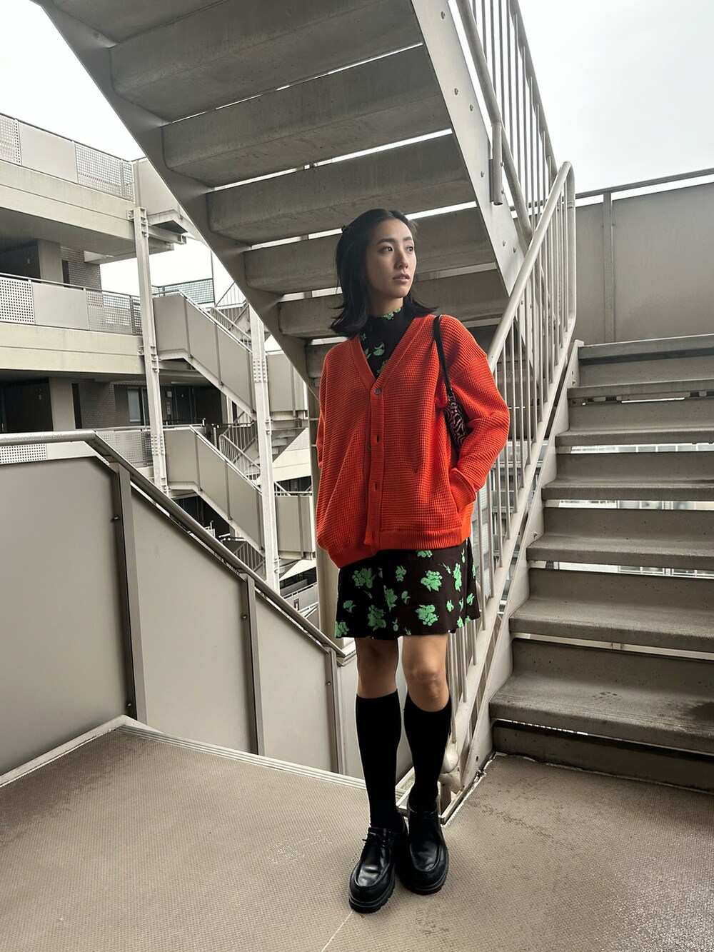 グリーン系のワンピース、オレンジ系のカーディガン/ボレロ、ピンク系のハンドバッグを着用したレディースの春コーディネートの3枚目の写真