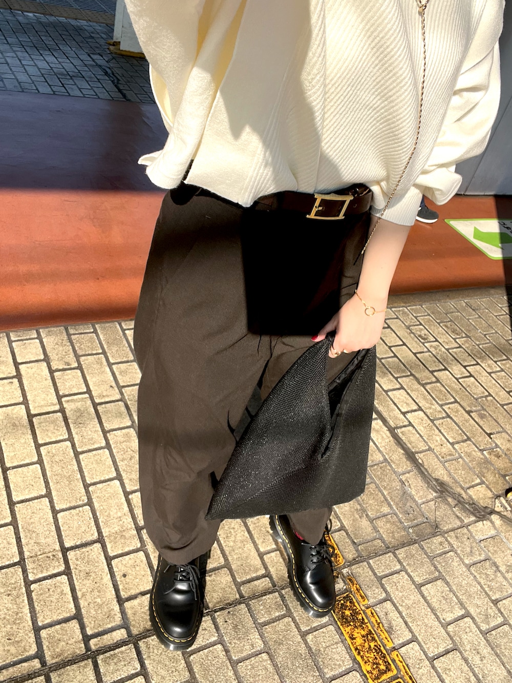 ホワイト系のニット/セーター、ブラック系のトートバッグ、グレー系のスラックスを着用したレディースの秋コーディネートの3枚目の写真