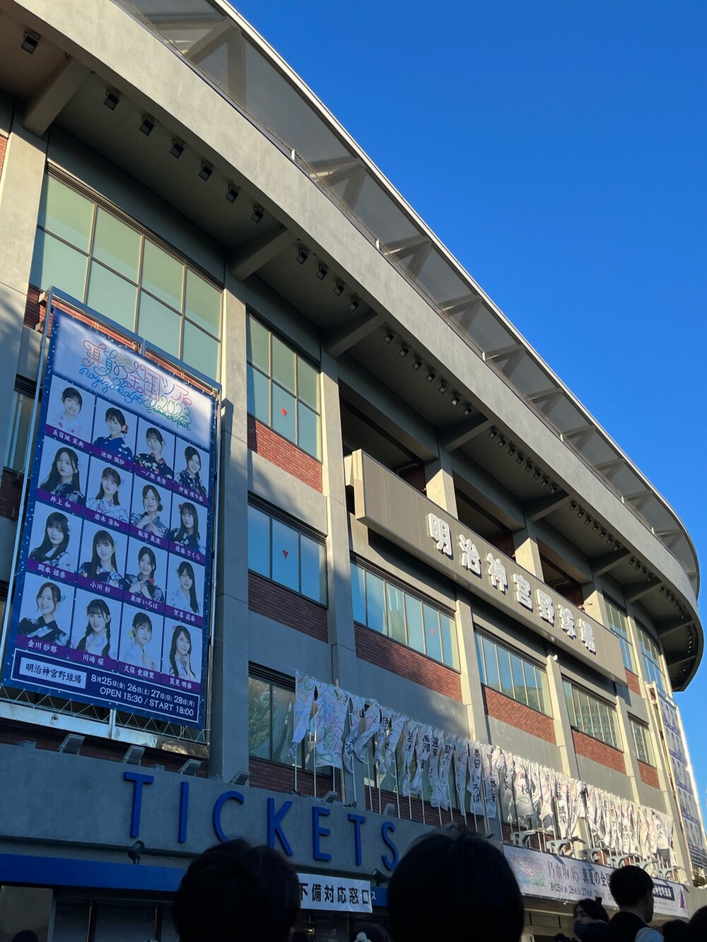 ブラック系のワンピース、ベージュ系のトートバッグ、ブルー系のスニーカーを着用したレディースの夏コーディネートの2枚目の写真