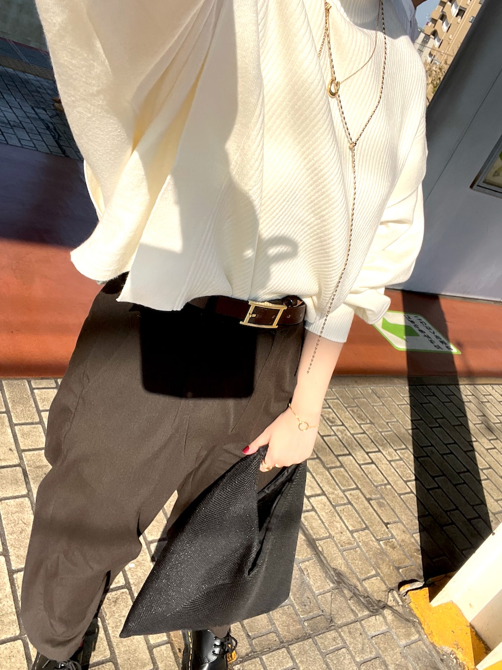 ホワイト系のニット/セーター、ブラック系のトートバッグ、グレー系のスラックスを着用したレディースの秋コーディネートの2枚目の写真