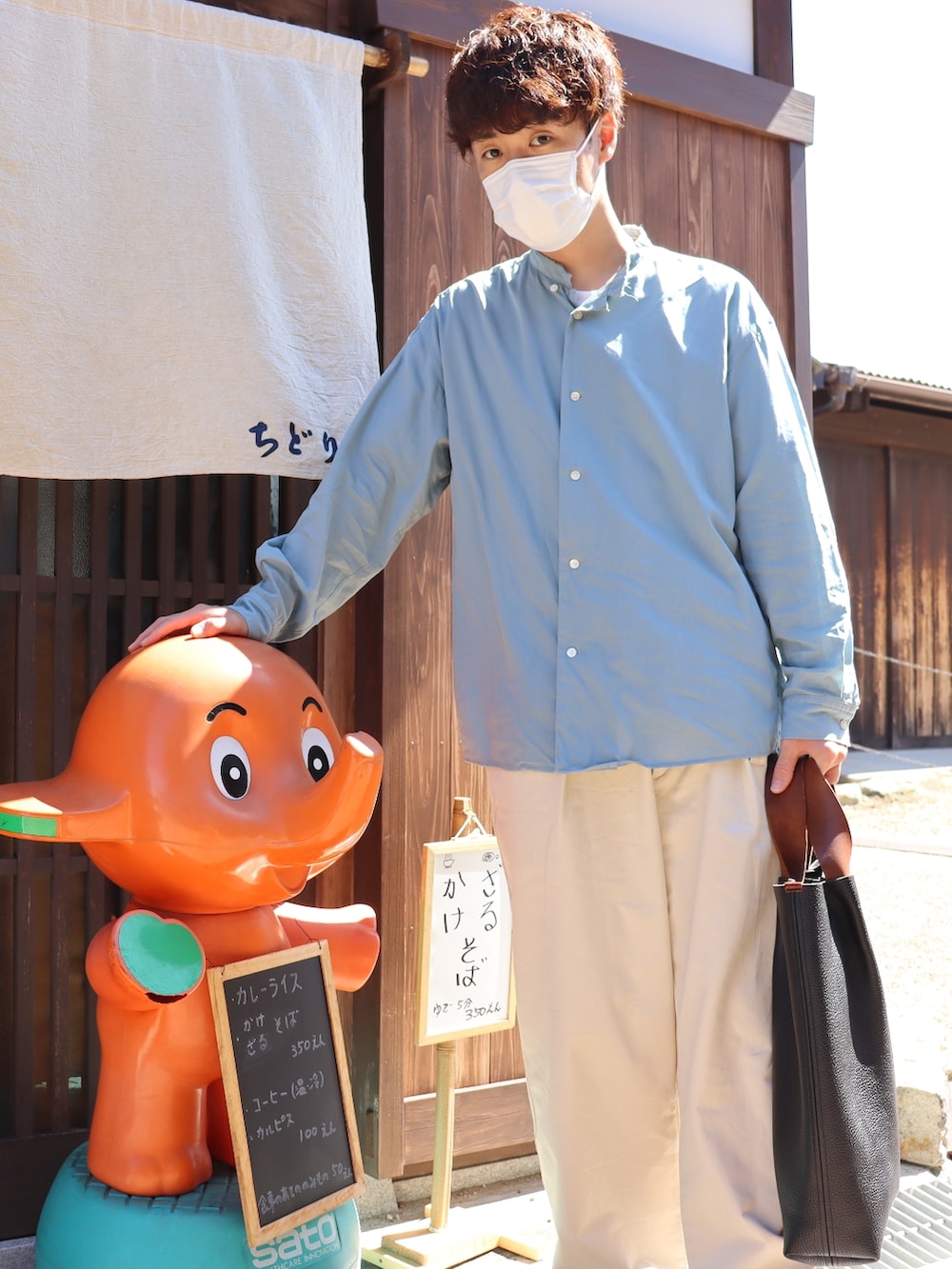 ブラウン系のトートバッグ、ブルー系のシャツ/ブラウス、ホワイト系のパンツを着用したメンズの秋コーディネートの2枚目の写真