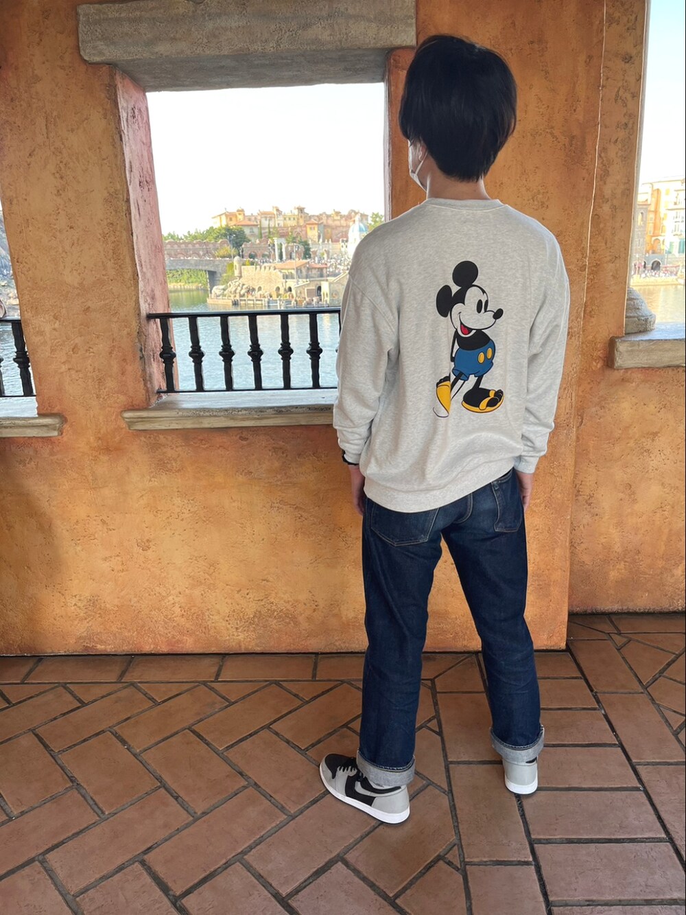 グレー系のスウェット、ブルー系のデニムパンツ、ブラック系のスニーカーを着用したメンズの春コーディネートの2枚目の写真