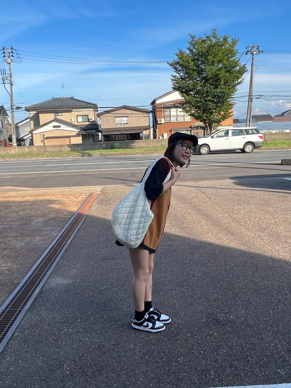 ブラック系のポロシャツ、ホワイト系のスニーカー、ブラック系のデニムパンツを着用したレディースの秋コーディネートの2枚目の写真