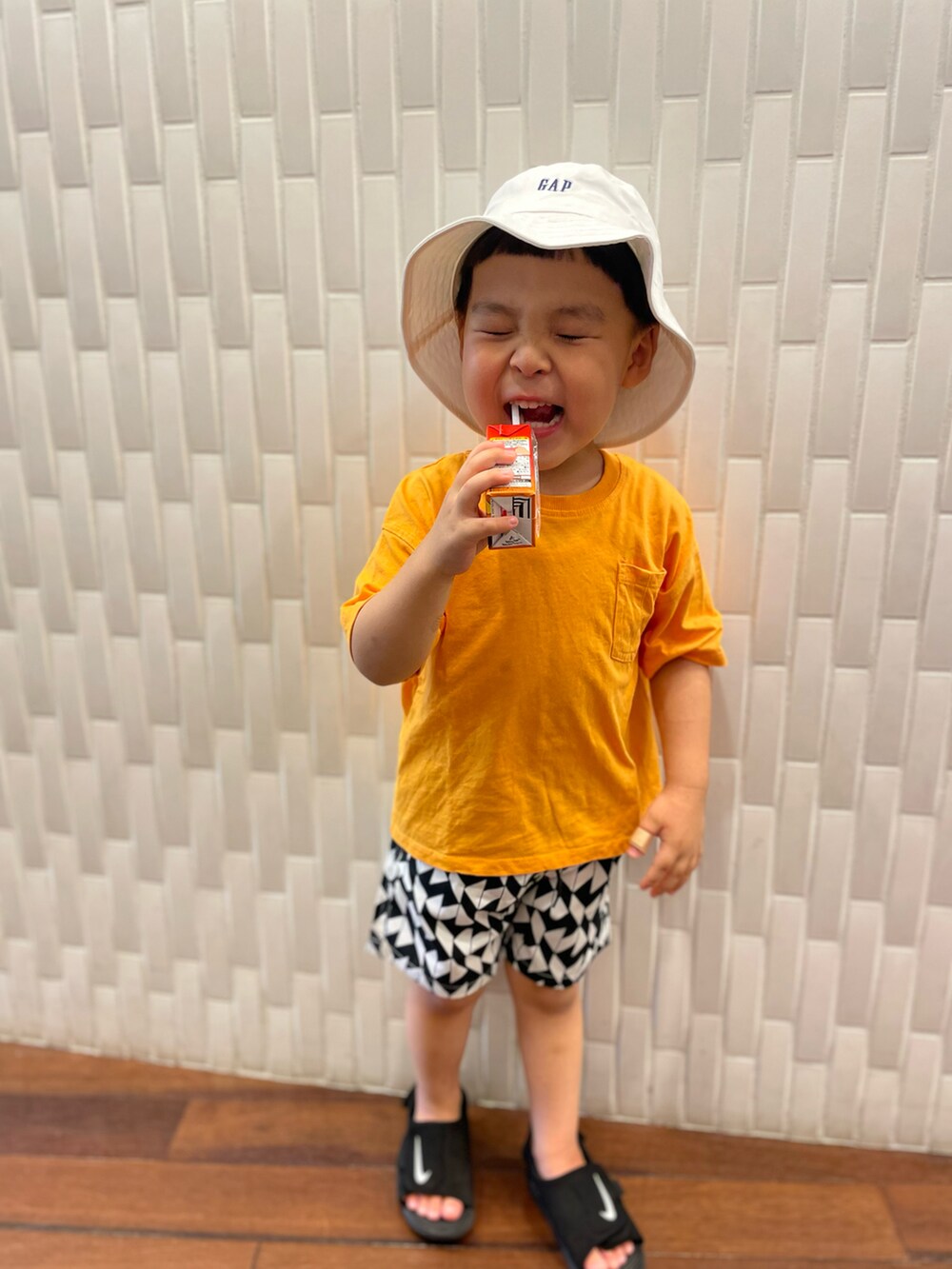 ブラック系のサンダル、その他のその他パンツ、オレンジ系のTシャツ/カットソーを着用したキッズの夏コーディネートの2枚目の写真