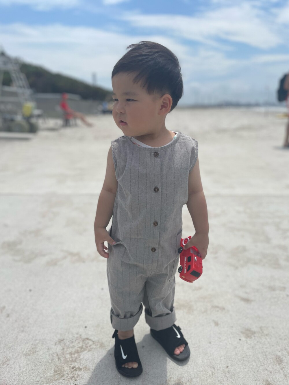 ブラック系のサンダル、グレー系のオールインワン・サロペットを着用したキッズの夏コーディネートの2枚目の写真