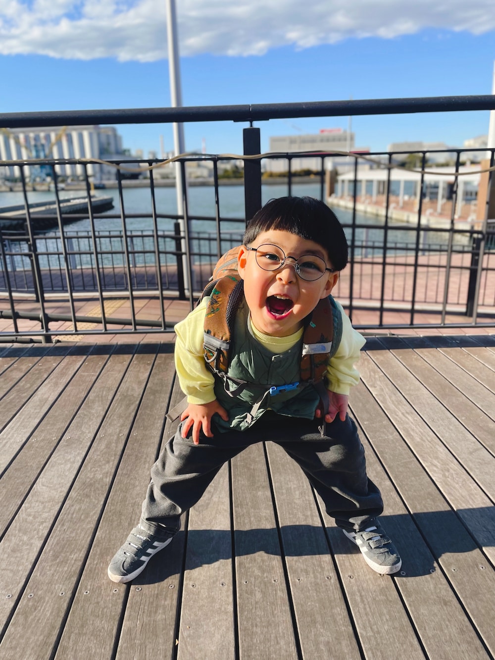 ブラック系のデニムパンツ、グリーン系のベスト、イエロー系のスウェットを着用したキッズの冬コーディネートの2枚目の写真