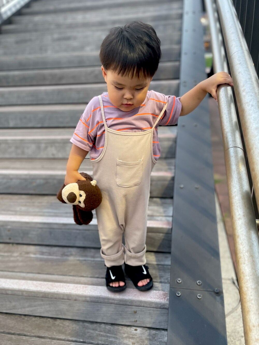 ブラック系のサンダル、パープル系のTシャツ/カットソー、ベージュ系のサロペット/オーバーオールを着用したキッズの夏コーディネートの2枚目の写真