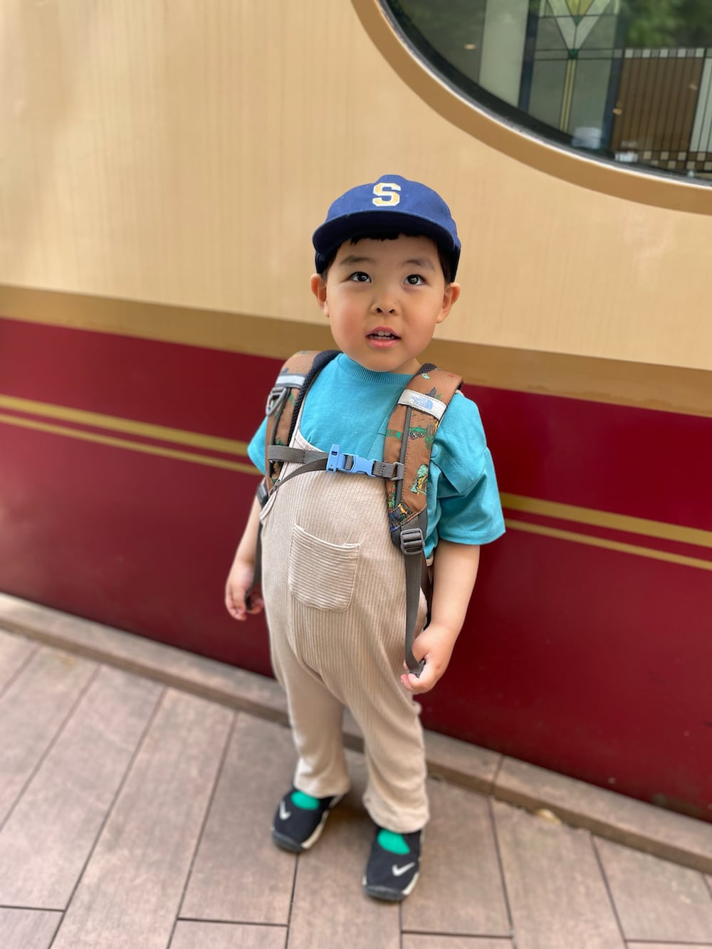 ブラック系のスニーカー、ベージュ系のサロペット/オーバーオール、ブラウン系のバックパック/リュックを着用したキッズの春コーディネートの2枚目の写真