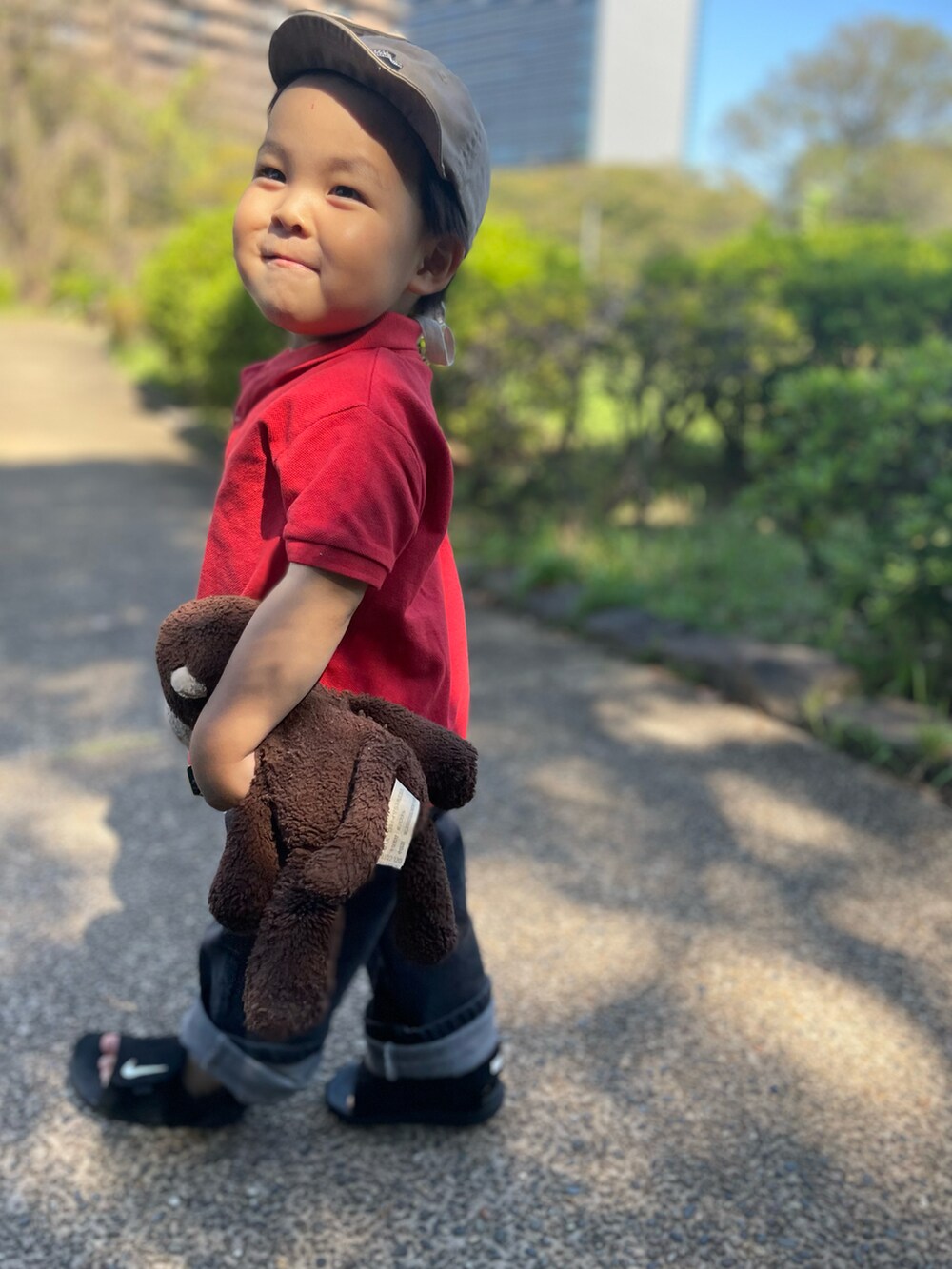 レッド系のポロシャツ、ブラック系のデニムパンツ、ブラック系のサンダルを着用したキッズの秋コーディネートの2枚目の写真