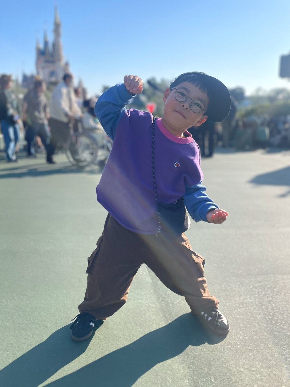 パープル系のスウェット、ブラック系のショルダーバッグ、ブラウン系のカーゴパンツを着用したキッズの冬コーディネートの2枚目の写真