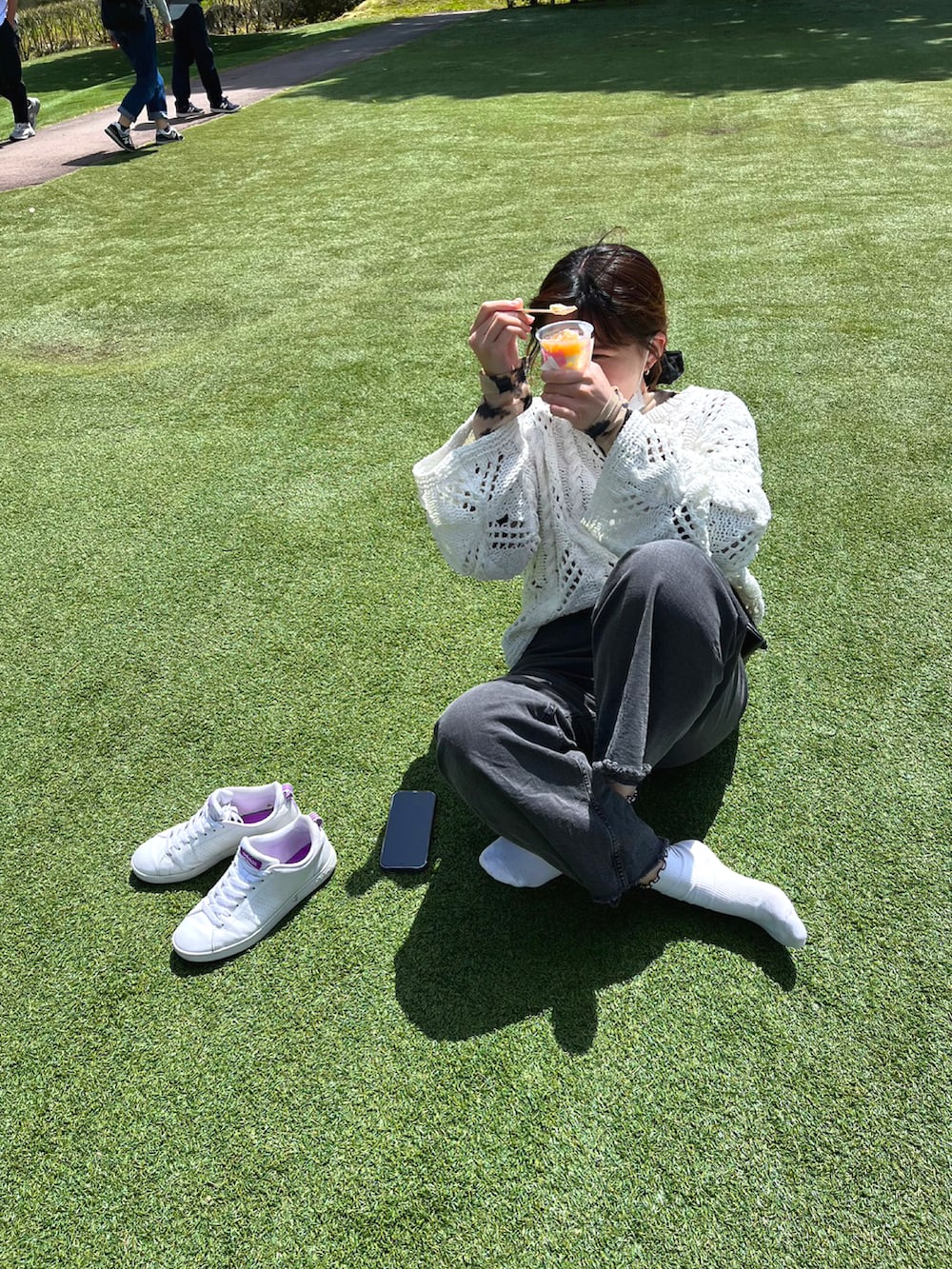 ブラック系のデニムパンツ、ホワイト系のスニーカー、ブラック系のショルダーバッグを着用したレディースの夏コーディネートの3枚目の写真