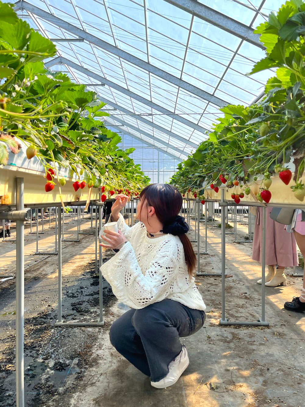 ブラック系のデニムパンツ、ホワイト系のスニーカー、ブラック系のショルダーバッグを着用したレディースの夏コーディネートの4枚目の写真