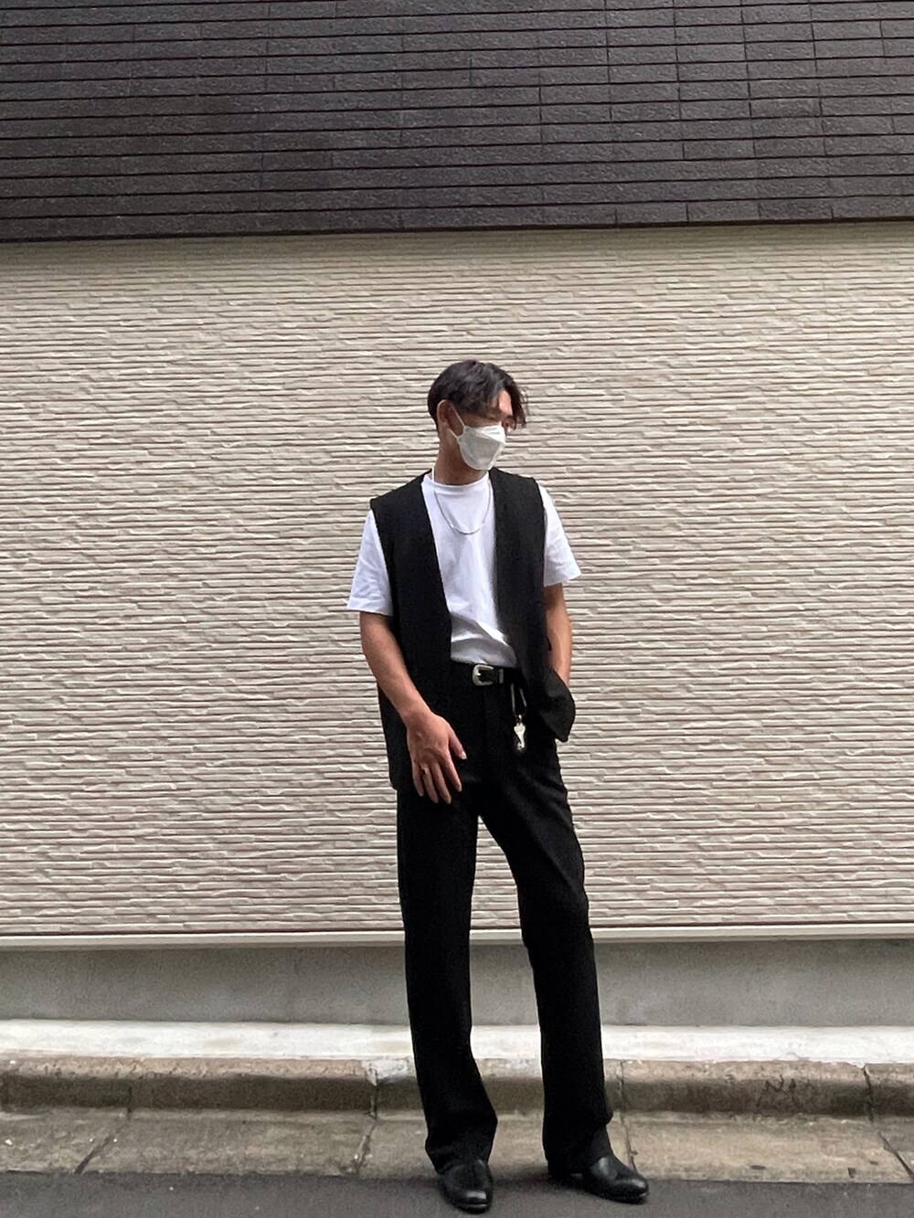 ブラック系のベスト、ホワイト系のTシャツ/カットソー、ブラック系のスラックスを着用したメンズの冬コーディネートの2枚目の写真