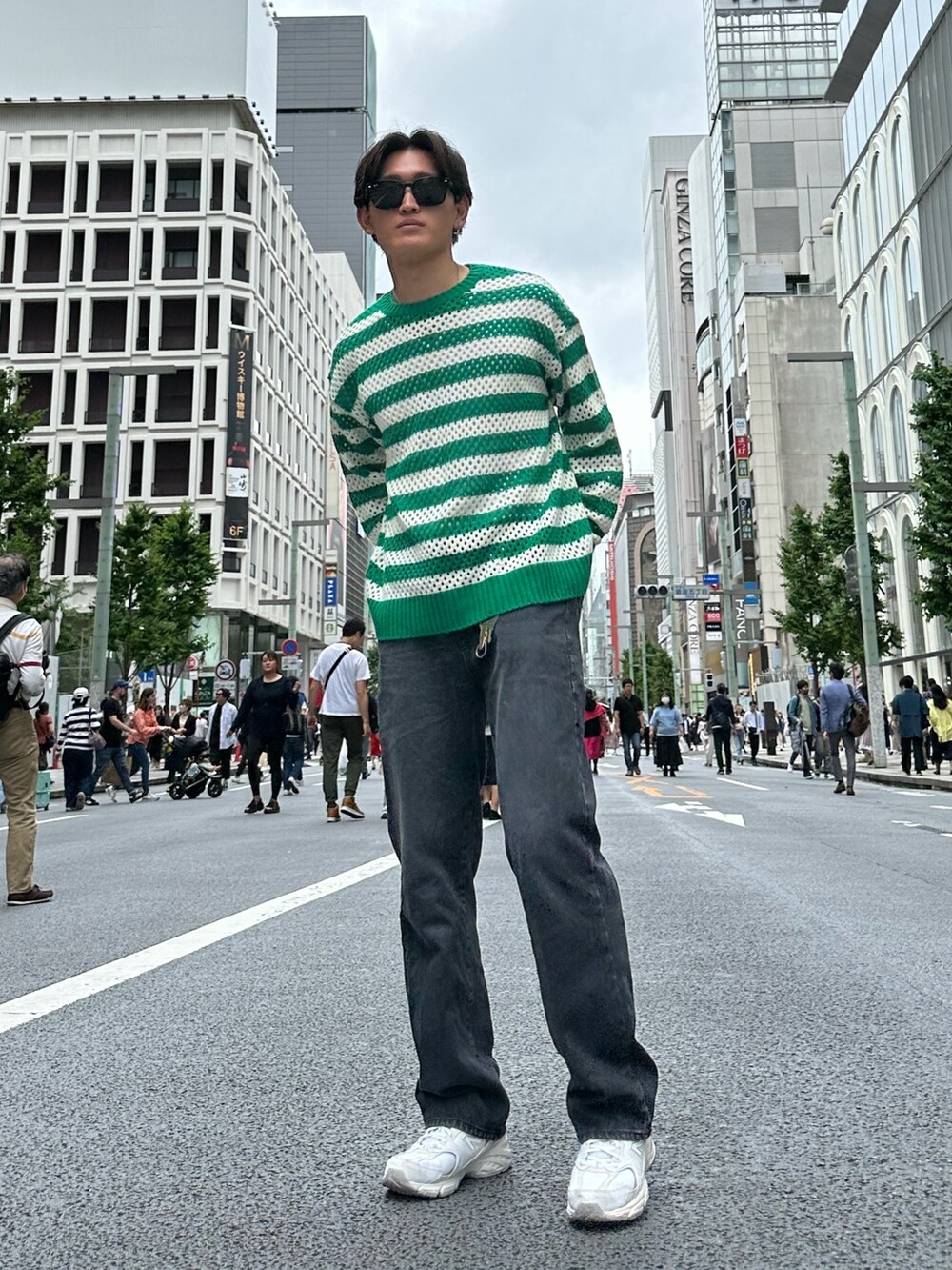 グリーン系のニット/セーター、グレー系のデニムパンツ、ホワイト系のスニーカーを着用したメンズの春コーディネートの2枚目の写真