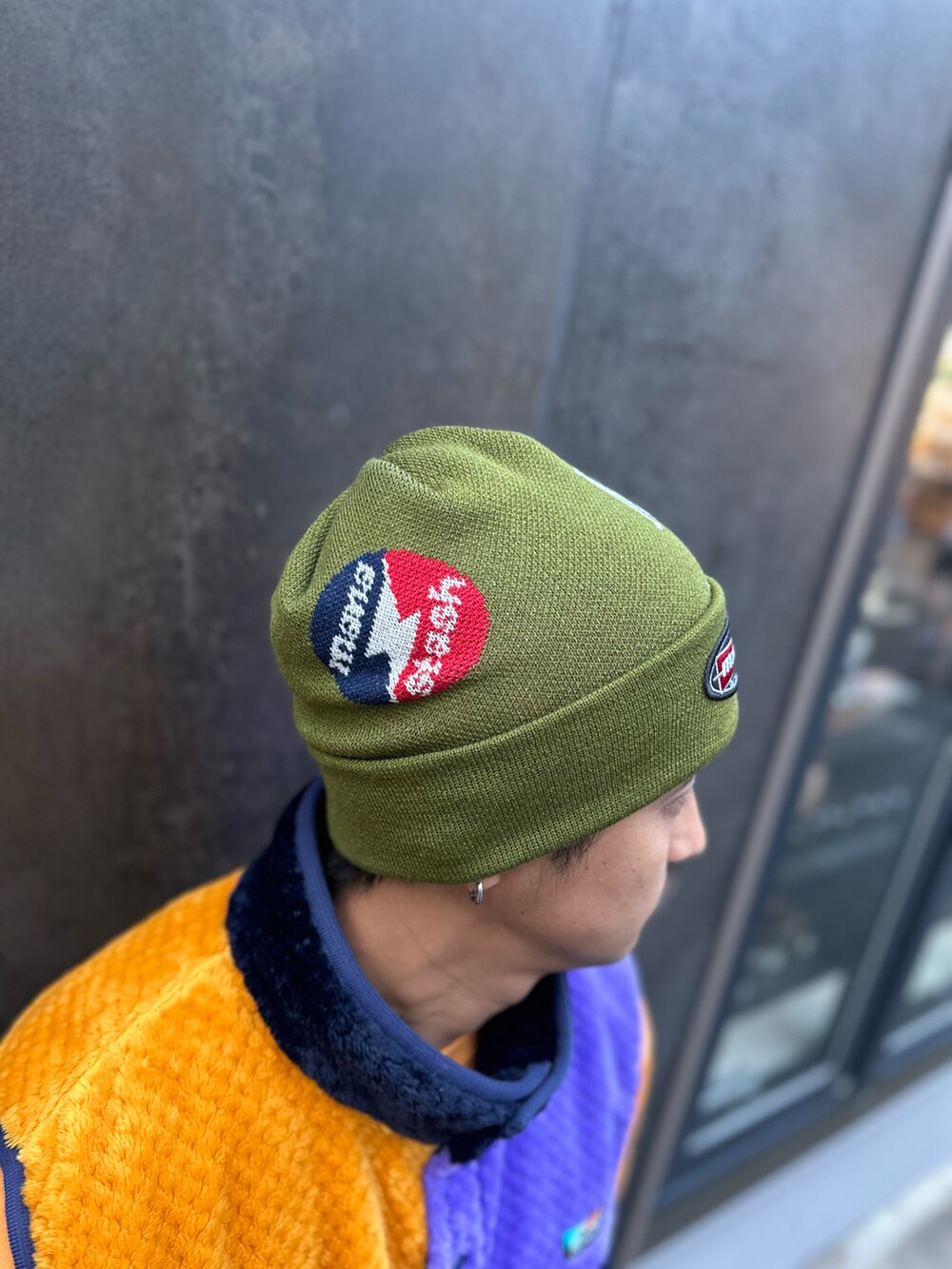 オレンジ系のスウェット、グレー系のカーゴパンツ、グリーン系のニットキャップ/ビーニーを着用したメンズの秋コーディネートの5枚目の写真