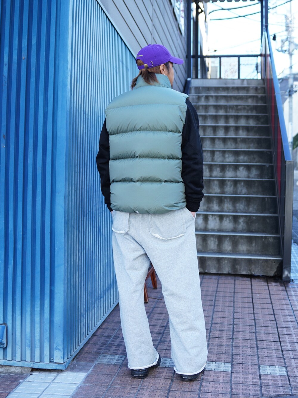 グレー系のスウェットパンツ、グリーン系のダウンベスト、ブラック系のブルゾンを着用したメンズの冬コーディネートの3枚目の写真