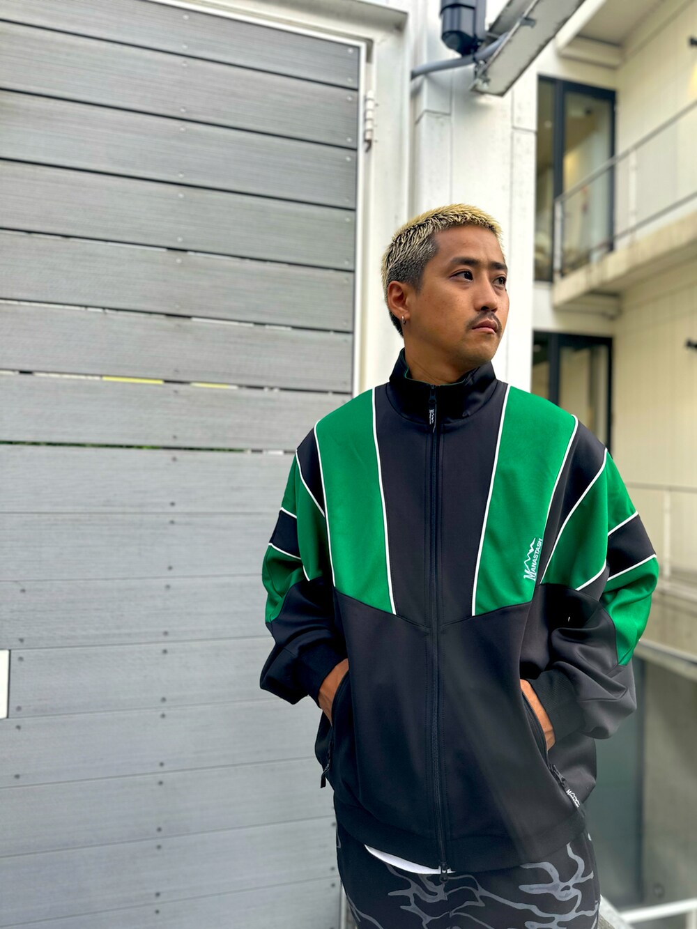 グリーン系のブルゾン、ブラック系のスウェットパンツ、ブラウン系のモカシン/デッキシューズを着用したメンズの秋コーディネートの3枚目の写真