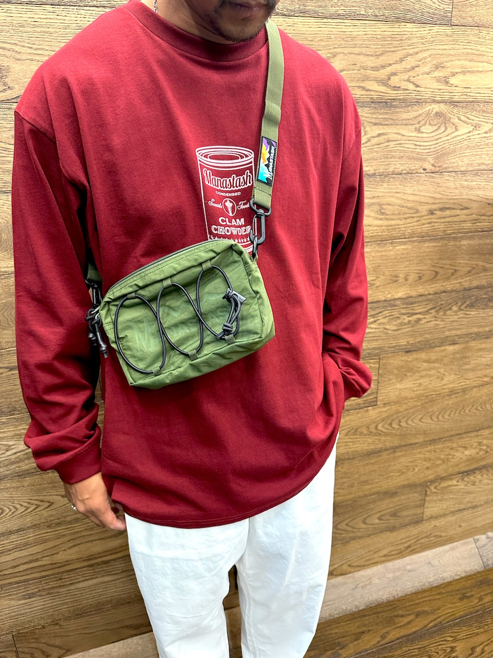 ホワイト系のその他パンツ、レッド系のTシャツ/カットソー、グリーン系のショルダーバッグを着用したメンズの夏コーディネートの2枚目の写真