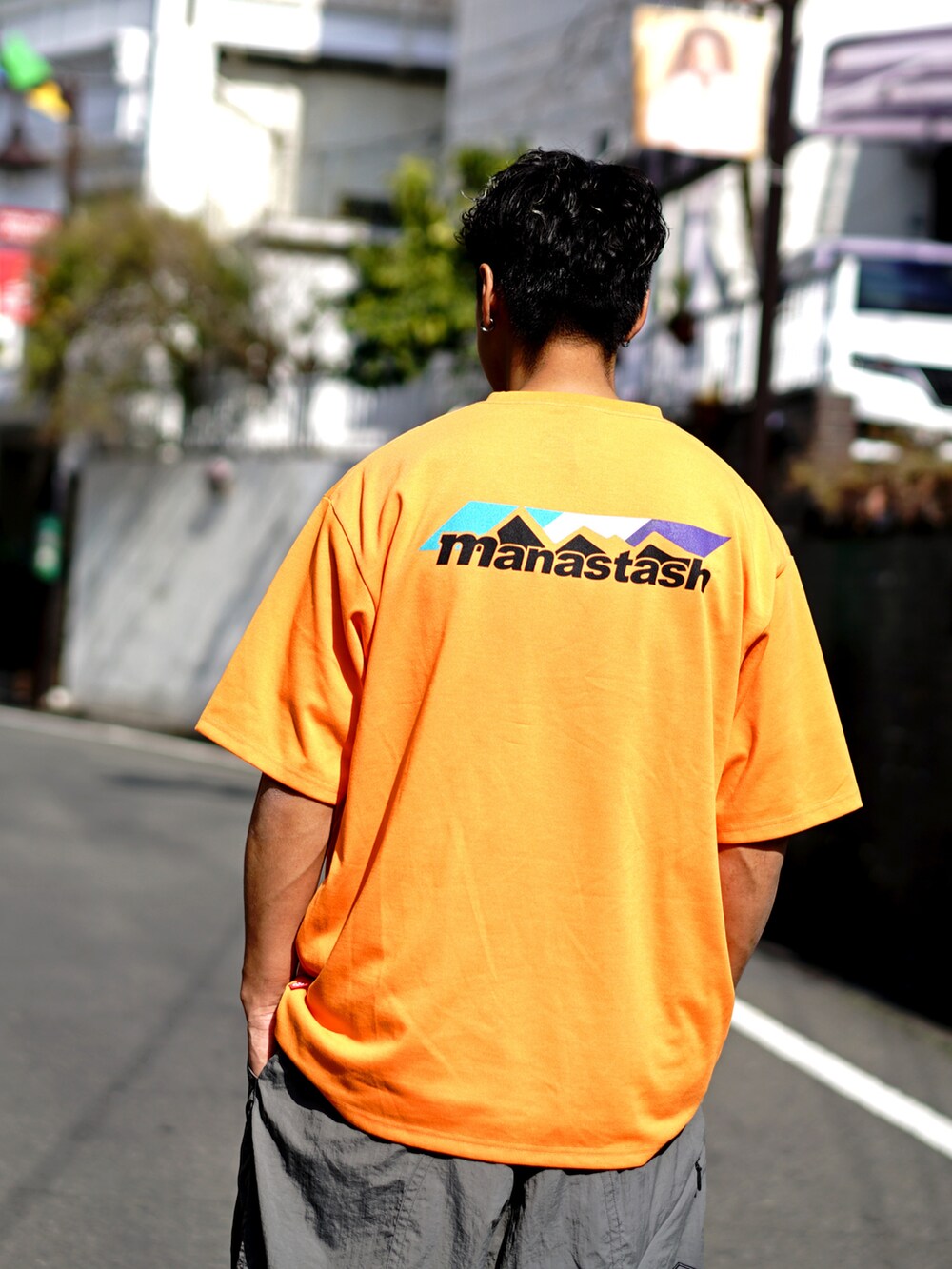 オレンジ系のTシャツ/カットソー、グレー系のその他パンツを着用したメンズの冬コーディネートの2枚目の写真