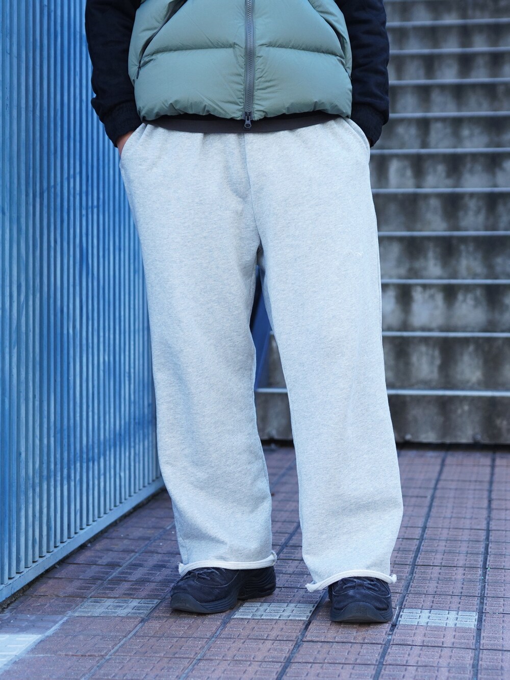 グレー系のスウェットパンツ、グリーン系のダウンベスト、ブラック系のブルゾンを着用したメンズの冬コーディネートの7枚目の写真