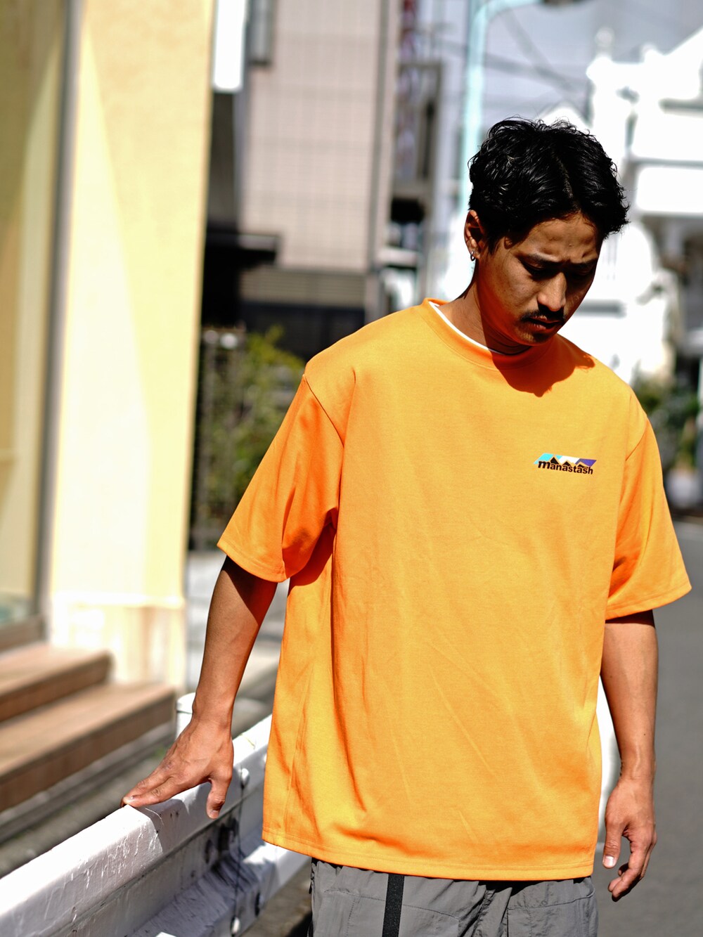 オレンジ系のTシャツ/カットソー、グレー系のその他パンツを着用したメンズの冬コーディネートの3枚目の写真