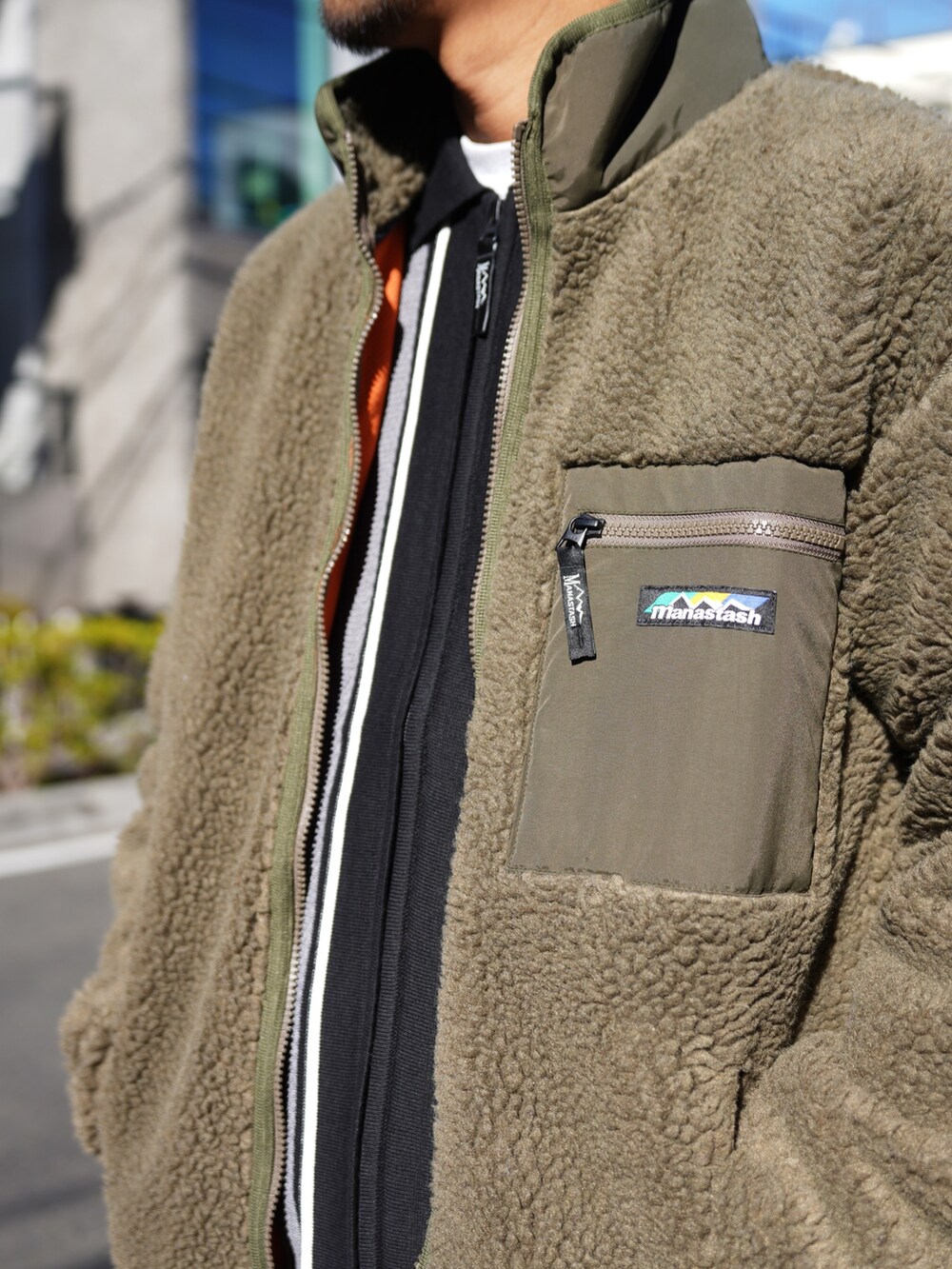 グリーン系のブルゾン、ブラック系のニット/セーターを着用したメンズの冬コーディネートの9枚目の写真