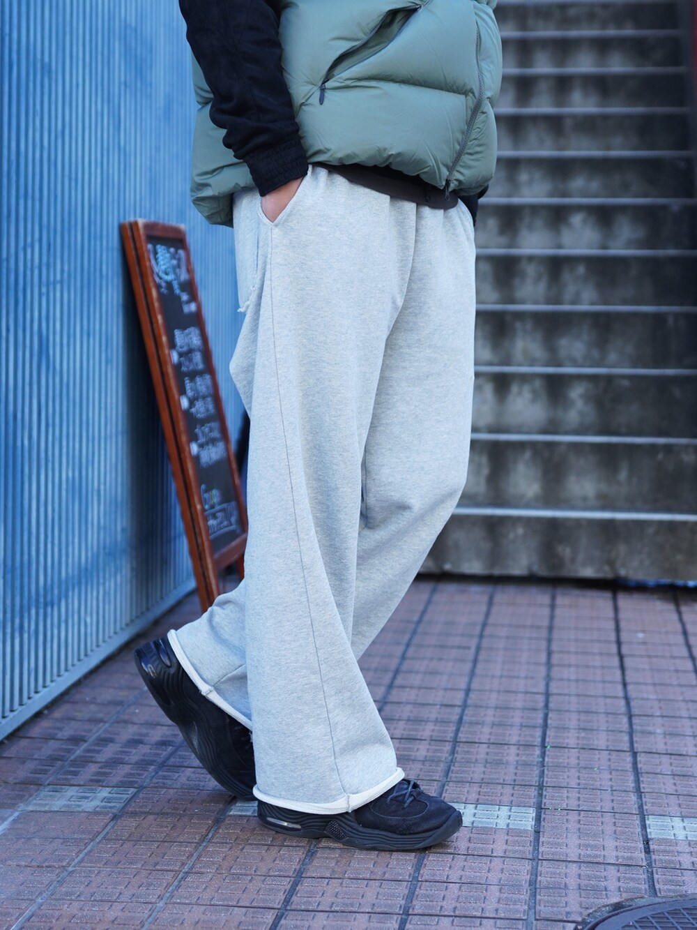 グレー系のスウェットパンツ、グリーン系のダウンベスト、ブラック系のブルゾンを着用したメンズの冬コーディネートの5枚目の写真