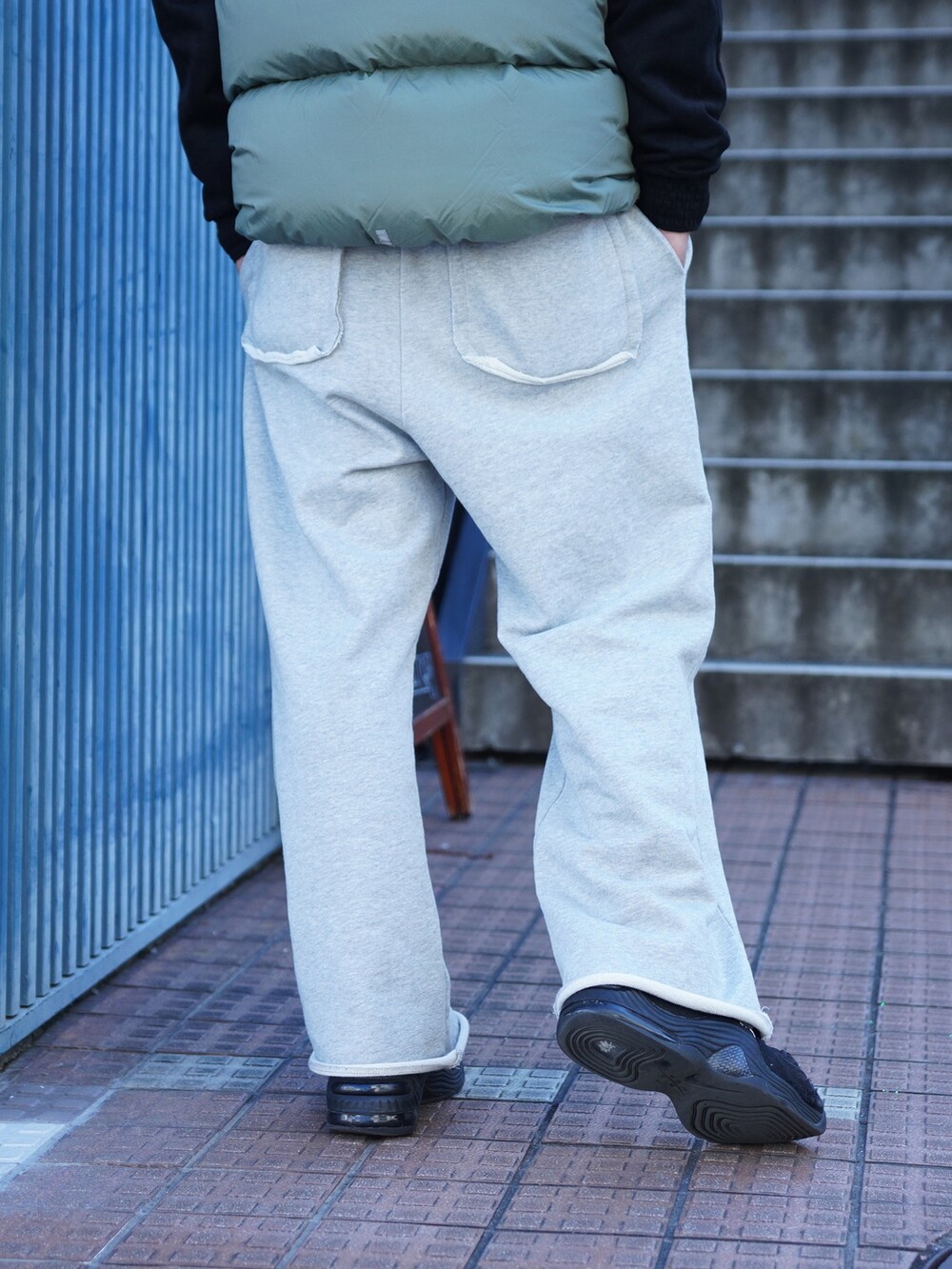 グレー系のスウェットパンツ、グリーン系のダウンベスト、ブラック系のブルゾンを着用したメンズの冬コーディネートの4枚目の写真