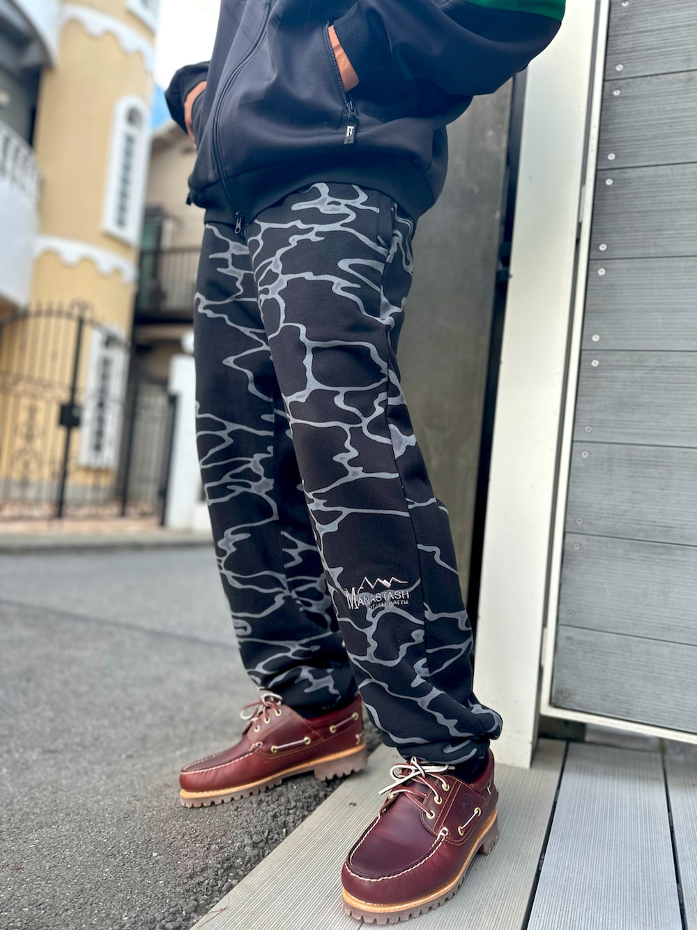 グリーン系のブルゾン、ブラック系のスウェットパンツ、ブラウン系のモカシン/デッキシューズを着用したメンズの秋コーディネートの4枚目の写真