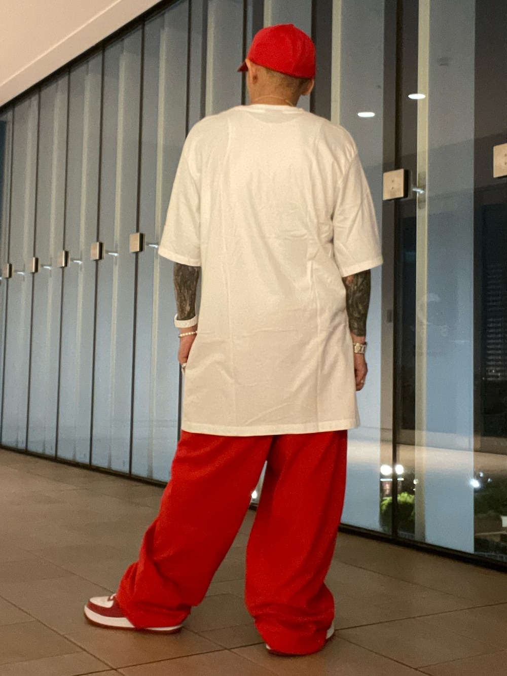 ホワイト系のTシャツ/カットソー、ホワイト系のタンクトップ、レッド系のスウェットパンツを着用したメンズの夏コーディネートの2枚目の写真