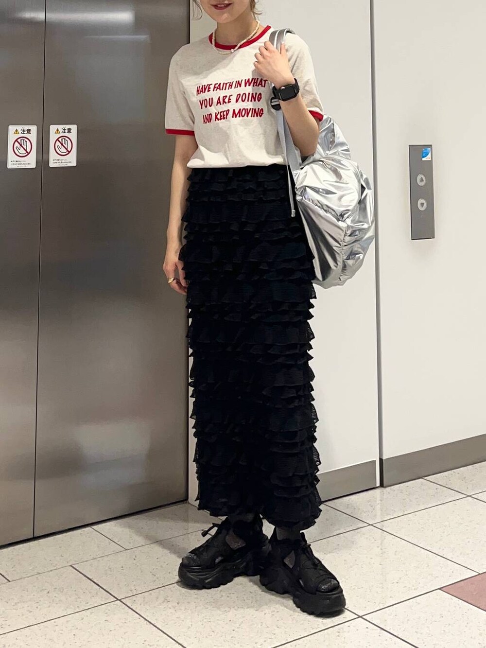 ブラック系のサンダル、ブラック系のスカート、シルバー系のバックパック/リュックを着用したレディースの春コーディネートの2枚目の写真