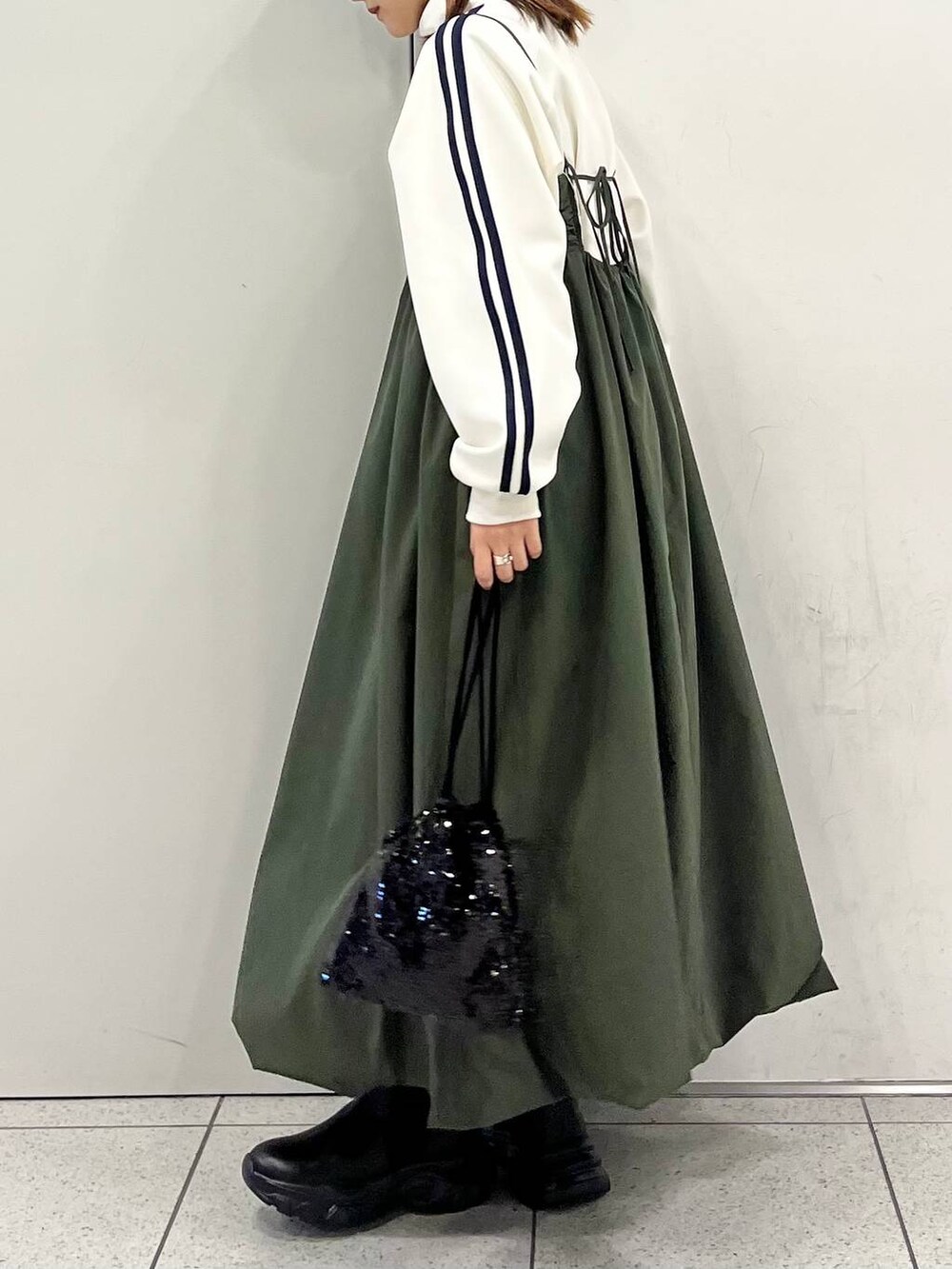 ブラック系のハンドバッグ、グリーン系のワンピース、ブラック系のブーツを着用したレディースの冬コーディネートの3枚目の写真