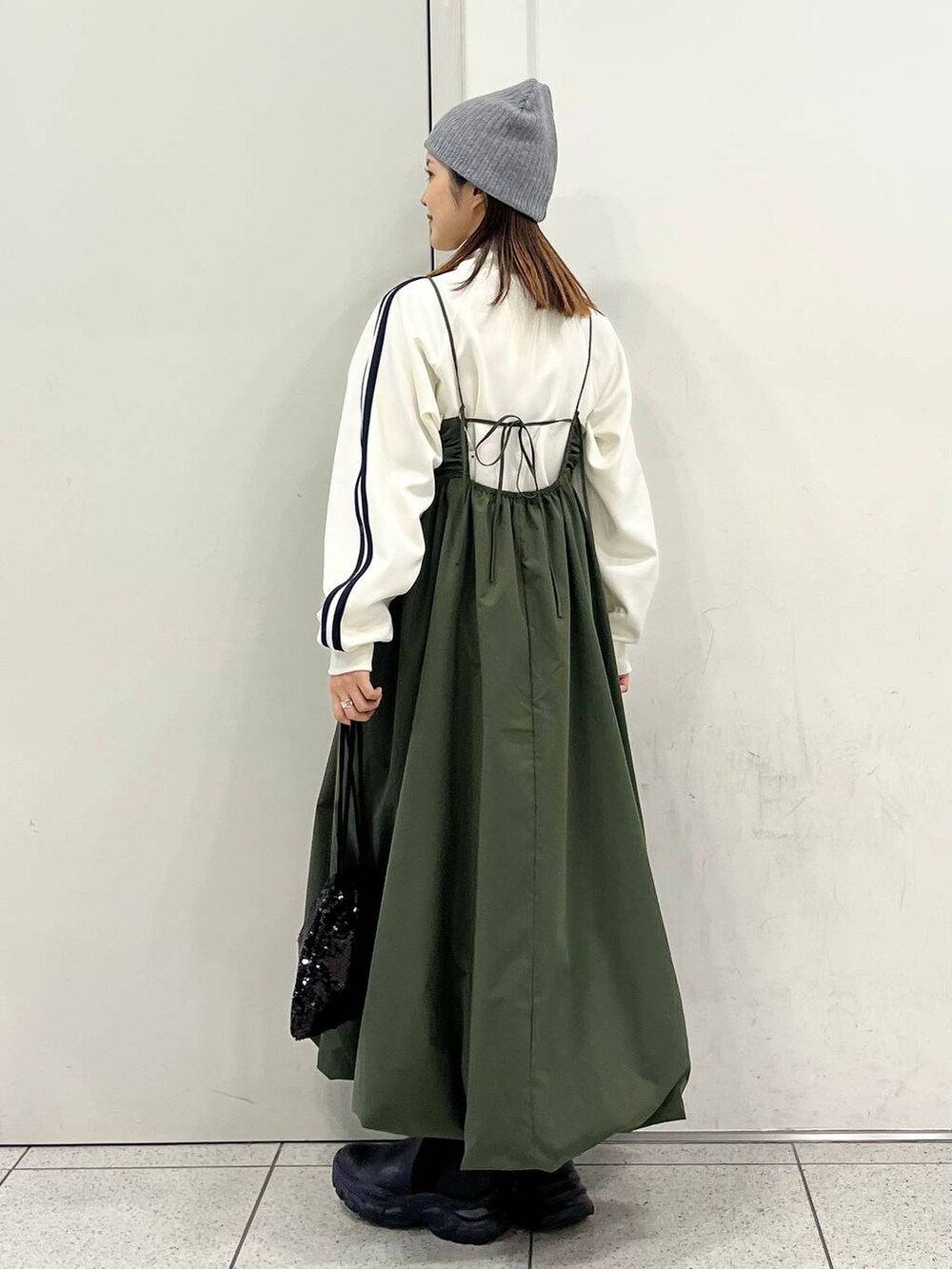 ブラック系のハンドバッグ、グリーン系のワンピース、ブラック系のブーツを着用したレディースの冬コーディネートの5枚目の写真