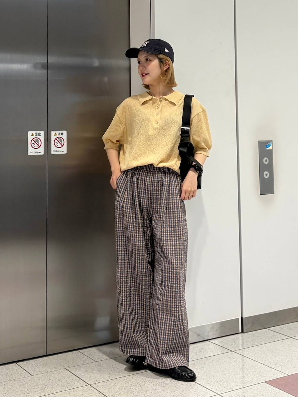 ブラック系のローファー、ブラック系のショルダーバッグ、ベージュ系のTシャツ/カットソーを着用したレディースの夏コーディネートの4枚目の写真